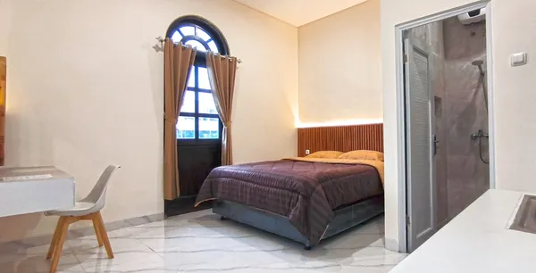 Sudut kamar tidur AVILITA House dengan jendela natural dan tirai blackout untuk istirahat